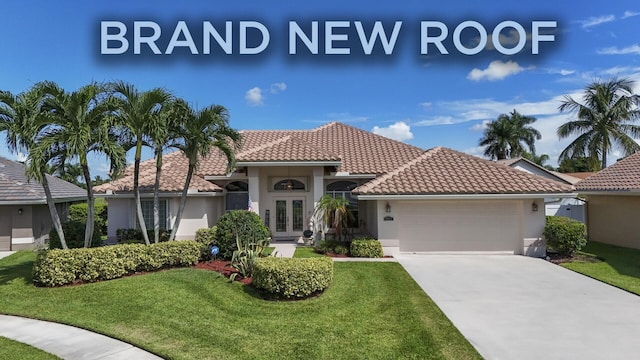 mediterranean / spanish home with a front lawn, a garage, and french doors