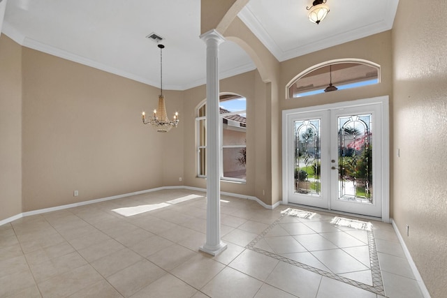 tiled foyer with ornate columns, crown molding, french doors, and a notable chandelier