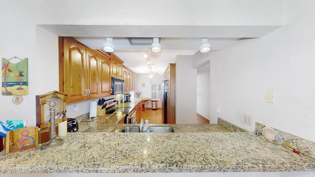 kitchen featuring kitchen peninsula, sink, beamed ceiling, and appliances with stainless steel finishes