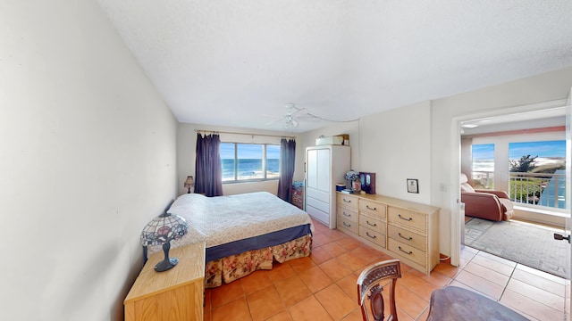 bedroom with a textured ceiling, a water view, and light tile patterned flooring