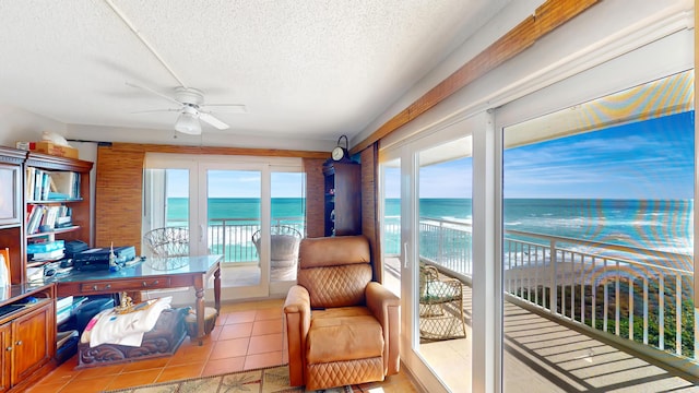 sunroom / solarium featuring a view of the beach, a water view, and ceiling fan