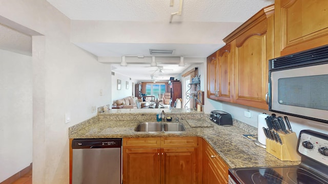 kitchen featuring appliances with stainless steel finishes, track lighting, a textured ceiling, ceiling fan, and sink