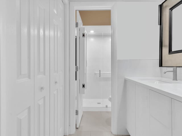 bathroom featuring a shower with door and vanity