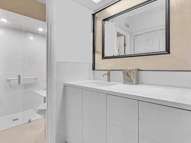 bathroom featuring a shower with door, vanity, toilet, and tile patterned flooring