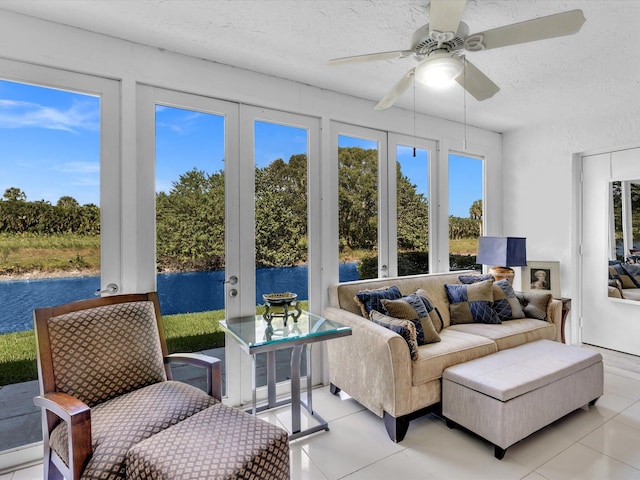 sunroom / solarium with a healthy amount of sunlight, a water view, and ceiling fan