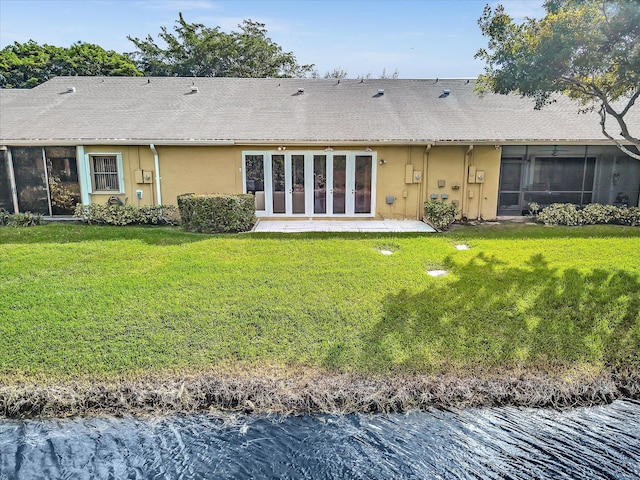 back of property featuring a yard, a sunroom, and a water view