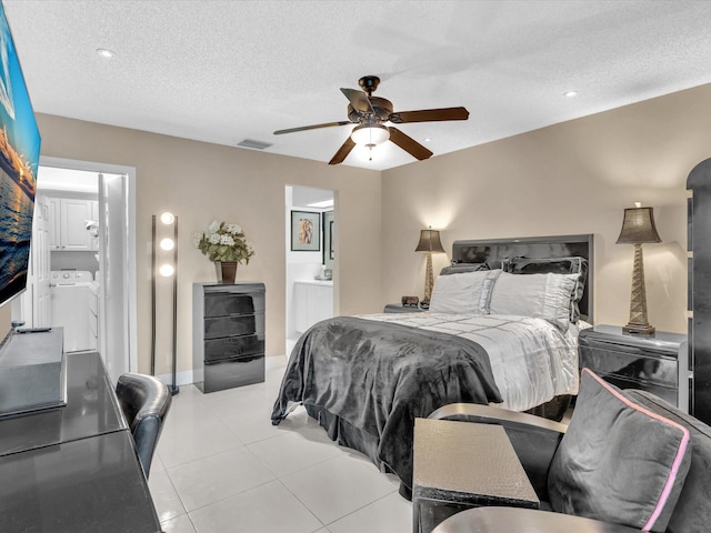 bedroom with ensuite bathroom, light tile patterned floors, a textured ceiling, ceiling fan, and washer and clothes dryer