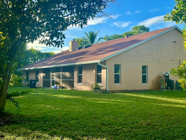 rear view of house with a sunroom and a lawn