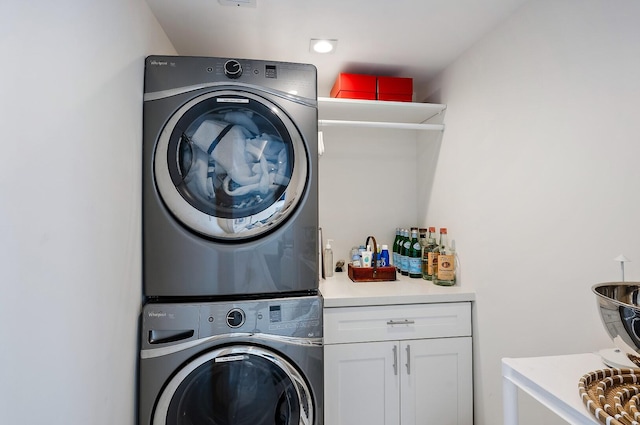 laundry area with cabinets and stacked washing maching and dryer