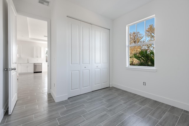 unfurnished bedroom with visible vents, multiple windows, a closet, and wood tiled floor