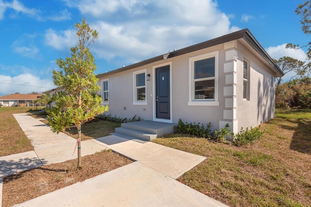 view of front of home with stucco siding and a front lawn