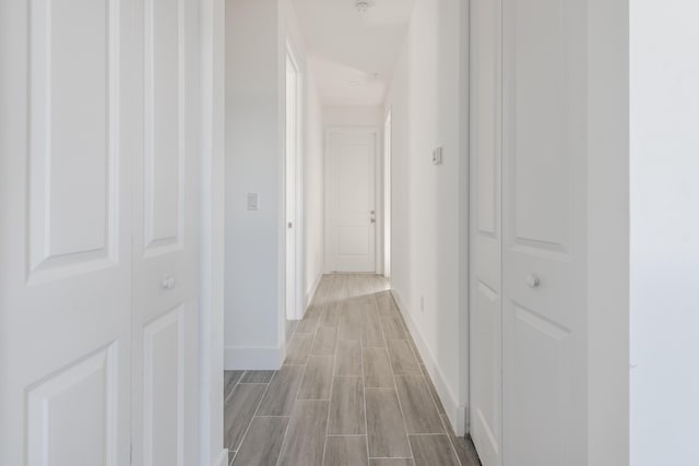 hall featuring baseboards and wood tiled floor