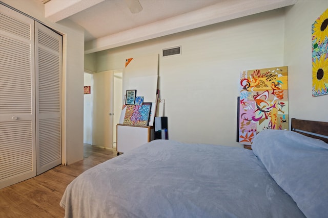 bedroom with beam ceiling, ceiling fan, a closet, and light hardwood / wood-style flooring