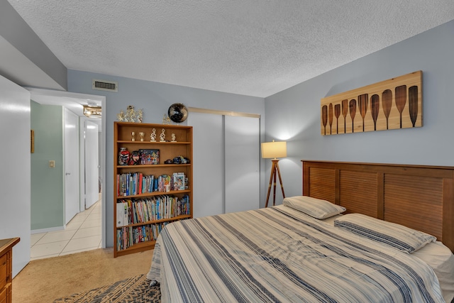 bedroom with a closet, a textured ceiling, and light colored carpet