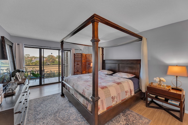 bedroom featuring access to outside, hardwood / wood-style floors, and a textured ceiling