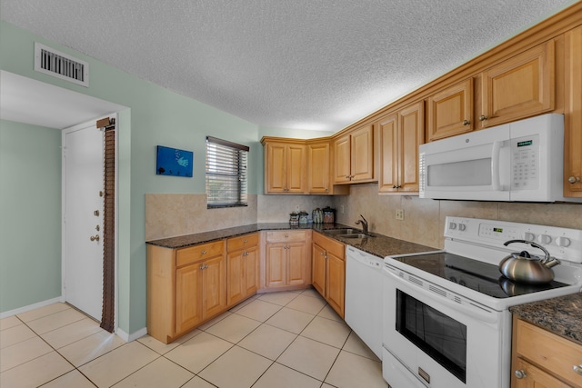 kitchen featuring a textured ceiling, sink, light tile patterned floors, and white appliances