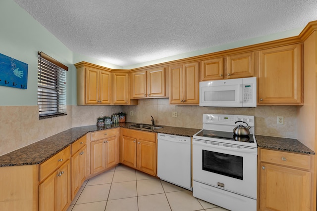 kitchen featuring sink, a textured ceiling, white appliances, and dark stone counters