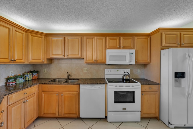 kitchen featuring sink, a textured ceiling, white appliances, and dark stone counters