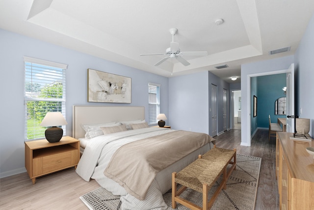 bedroom featuring a closet, ceiling fan, a raised ceiling, and hardwood / wood-style floors