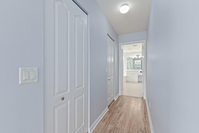 hall with a textured ceiling and light wood-type flooring