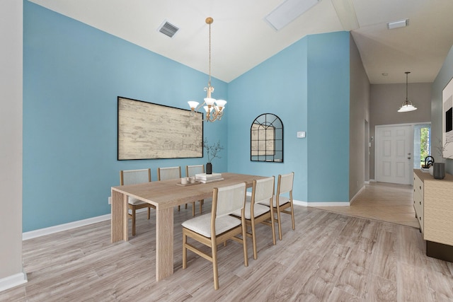 dining area featuring an inviting chandelier, high vaulted ceiling, and light hardwood / wood-style floors