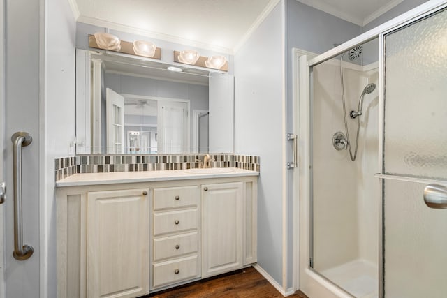 bathroom with wood-type flooring, backsplash, crown molding, vanity, and an enclosed shower