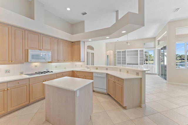 kitchen featuring light countertops, white appliances, light brown cabinets, and backsplash