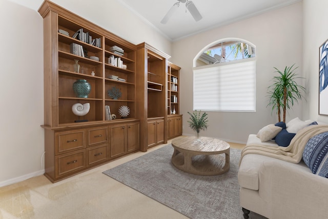 living area with ornamental molding, light colored carpet, baseboards, and a ceiling fan