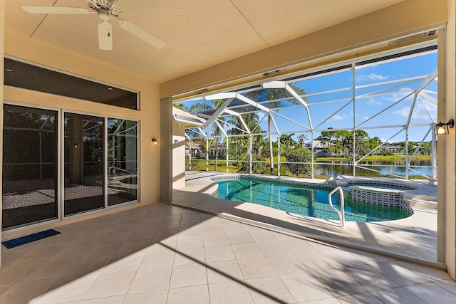 view of pool with a pool with connected hot tub, a water view, a patio area, ceiling fan, and a lanai