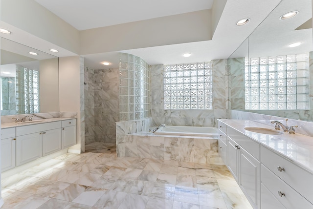 full bath with a bath, two vanities, and a sink