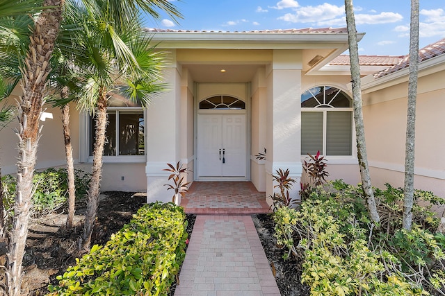 doorway to property with a tile roof and stucco siding