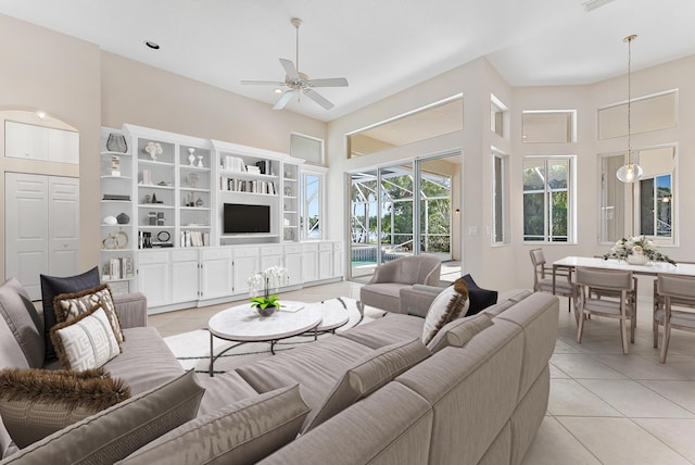 living room featuring a ceiling fan, light tile patterned flooring, and a high ceiling