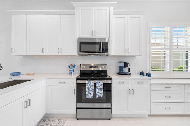 kitchen featuring white cabinets, stainless steel appliances, backsplash, and a sink