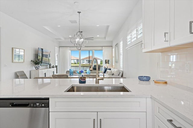 kitchen with white cabinets, a sink, open floor plan, dishwasher, and a notable chandelier