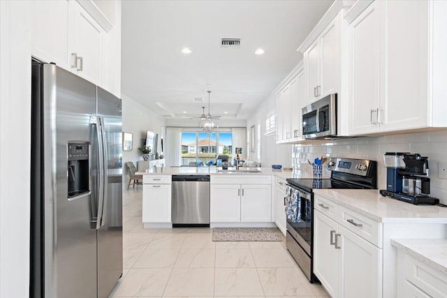 kitchen featuring appliances with stainless steel finishes, visible vents, a peninsula, and white cabinets