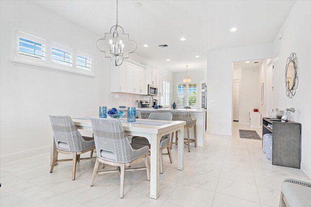 dining space featuring marble finish floor, an inviting chandelier, and baseboards