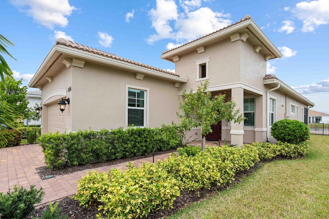 view of home's exterior featuring stucco siding, a tiled roof, a lawn, and fence