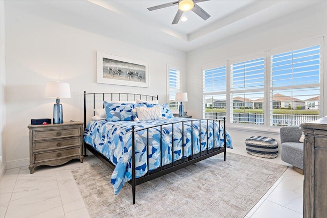 bedroom featuring a raised ceiling and ceiling fan