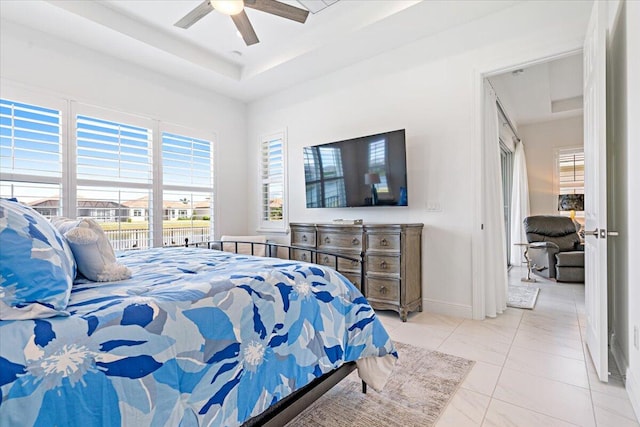 tiled bedroom with a tray ceiling and ceiling fan