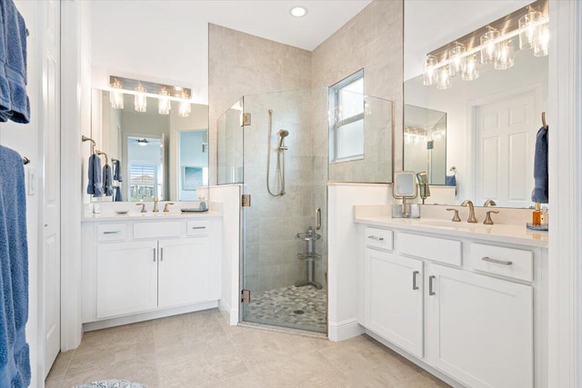 bathroom with a stall shower, two vanities, a sink, and a healthy amount of sunlight