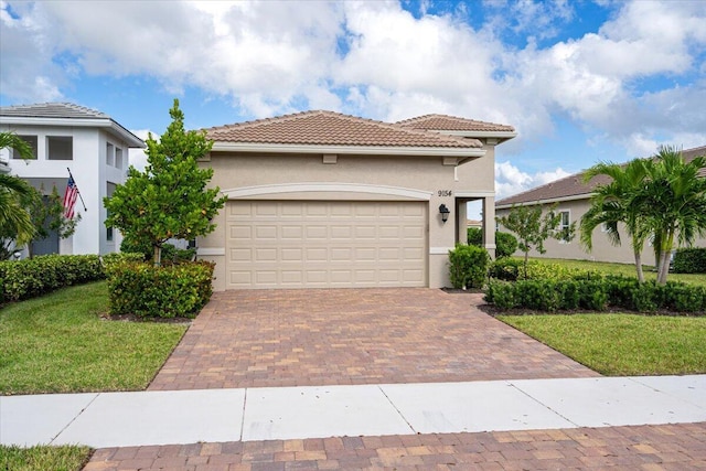 mediterranean / spanish-style home featuring stucco siding, decorative driveway, a front yard, and a garage