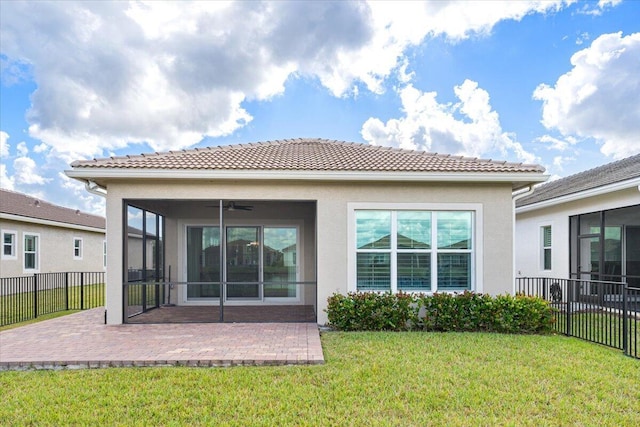 back of house with stucco siding, fence, a sunroom, a patio area, and a lawn