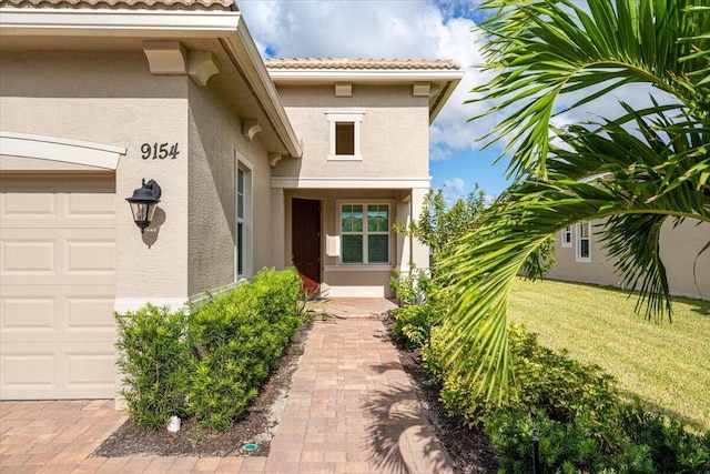 view of exterior entry with stucco siding and a tiled roof