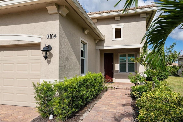 view of exterior entry featuring stucco siding and an attached garage