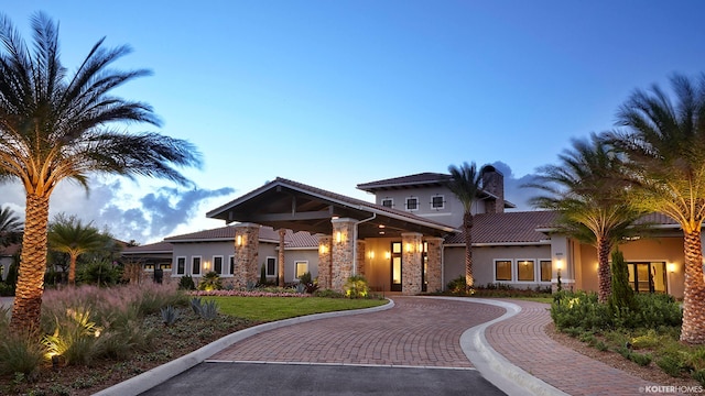 craftsman inspired home with stucco siding, a chimney, and uncovered parking