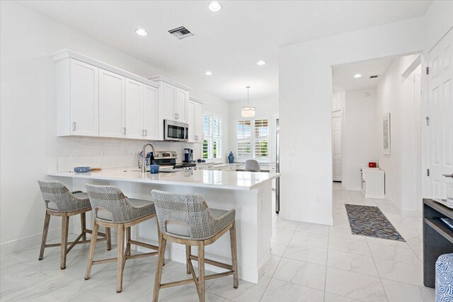 kitchen featuring stainless steel appliances, light countertops, a peninsula, and recessed lighting