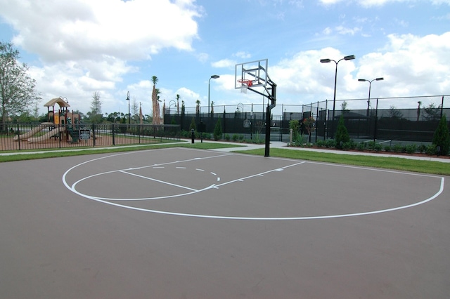 view of sport court featuring fence, playground community, and community basketball court