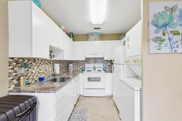 kitchen with white cabinets, white appliances, stacked washer and dryer, and a textured ceiling