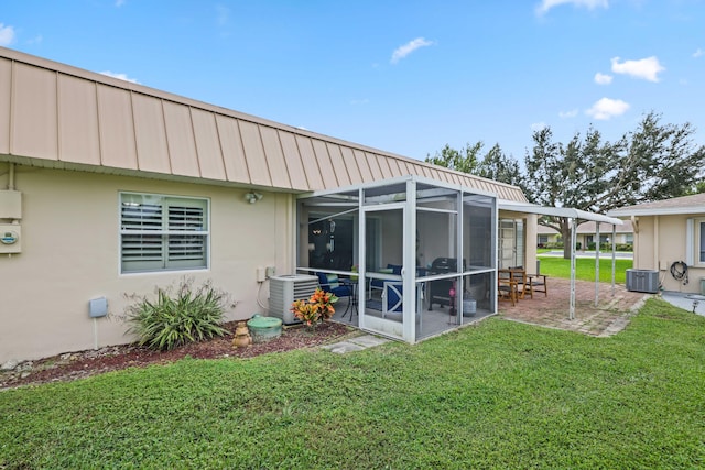 rear view of house featuring a yard, a patio, central AC unit, and a sunroom