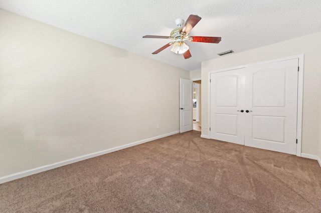 unfurnished bedroom with carpet flooring, ceiling fan, a closet, and a textured ceiling